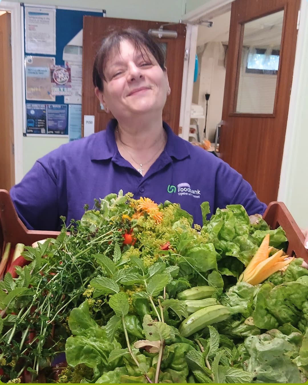 Volunteer holding a crate of organically grown vegetables and herbs