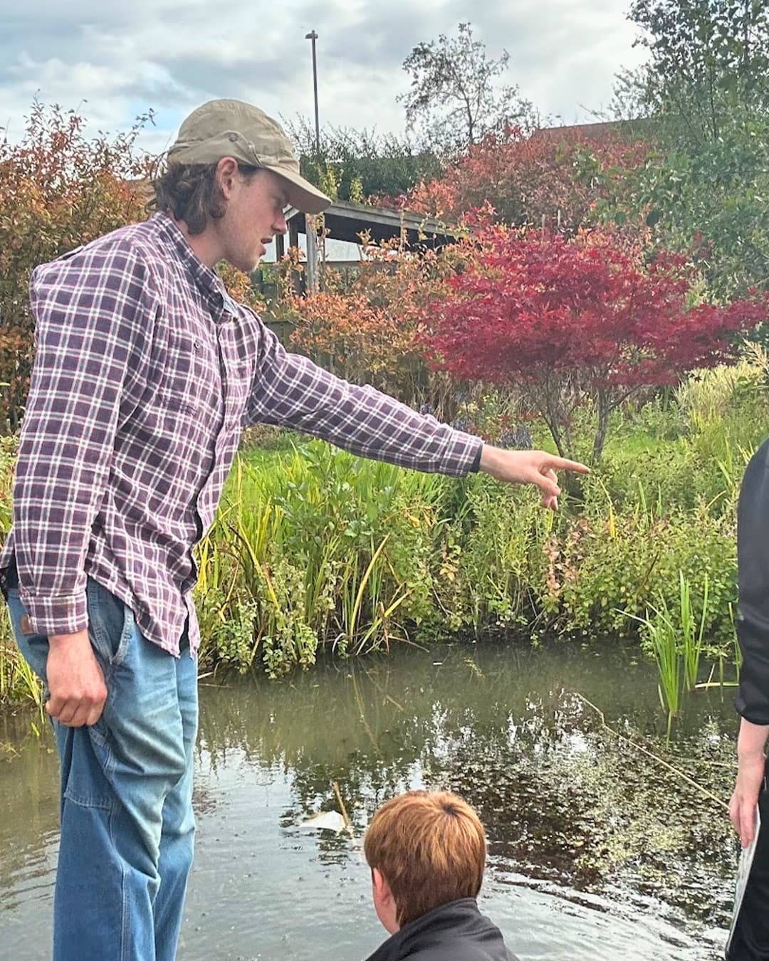 Community learning session beside a pond and planted habitat